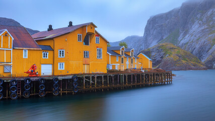 Nusfjord authentic fishing village with traditional yellow buildings. Lofoten islands, Norway. Blurred long exposure fjord water.