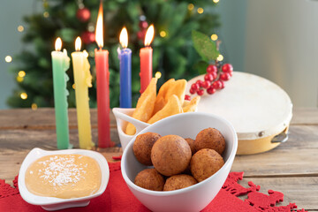 Candlelight Day. Typical Colombian food. Buñuelo, custard and flakes with candles and Christmas tree in the background. Colombian holiday.