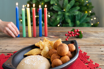 Candlelight Day. Typical Colombian food. Buñuelo, custard and flakes with candles and Christmas tree in the background. Colombian holiday.