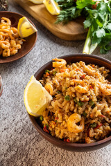 Serving the dish. Paella with lemon and fried prawns. Dish and herbs.