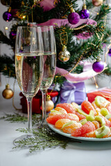 Christmas. Champagne glasses. fruits, panettone, tree with toys and garland.