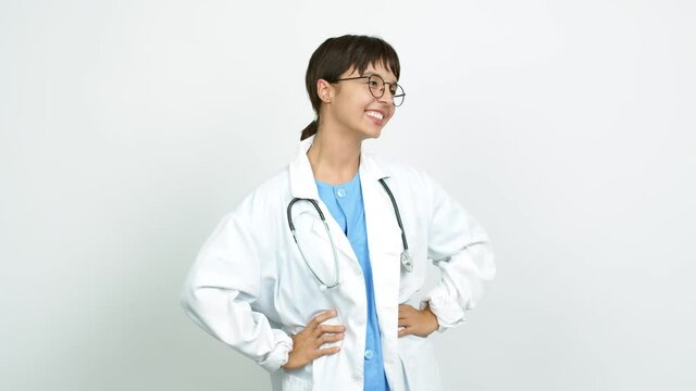 Young woman with nurse uniform posing with arms at hip and laughing over isolated background