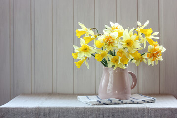 yellow daffodils in a jug on a table