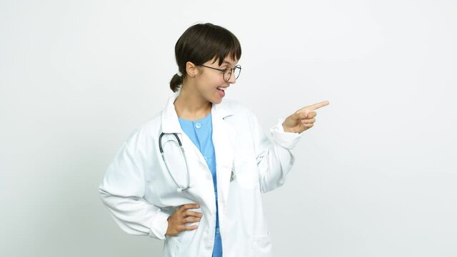 Young woman with nurse uniform pointing to the side and presenting a product while smiling over isolated background