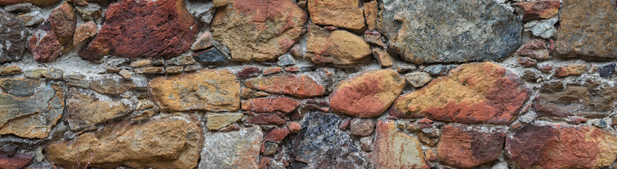 Old stone wall surface in abandoned building. Rough multicolored natural stone, texture panorama