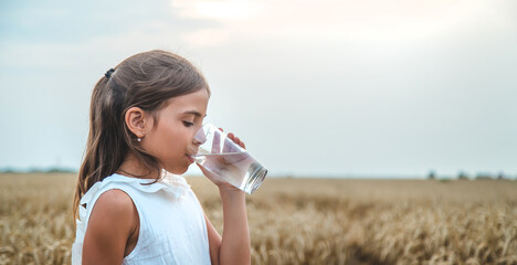 The child drinks water from a glass. Selective focus.