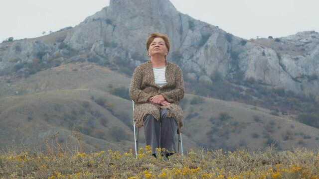 Portrait of an elderly woman against the background of an autumn mountain landscape