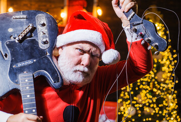 Bearded man in Santa costume with broken Electric guitar. Musical instrument. Rock guitarist. New...