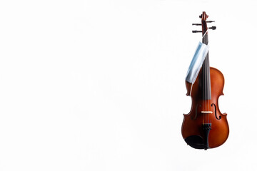 A brown violin or viola from wood on a white background with a medical mask hanging off of one of its pegs No.3