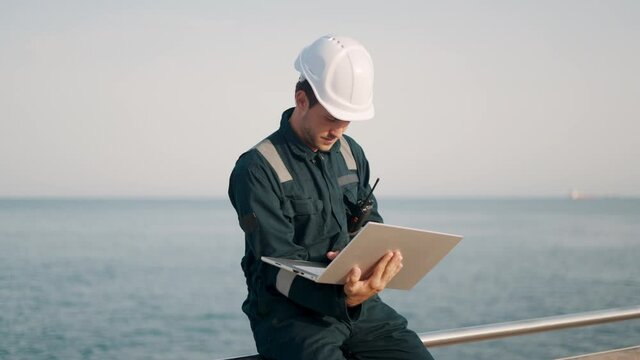 Focused man port inspector using laptop computer while working at dockside