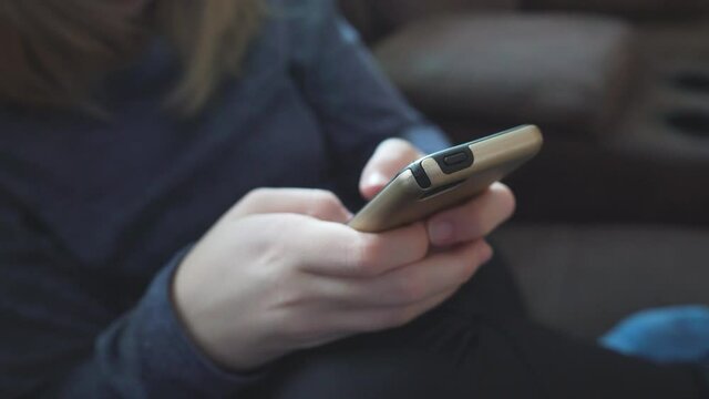 Close up Teen Girl Texting on her smartphone while sitting on a couch