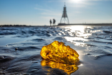Amber in the Wadden Sea in Cuxhaven, Germany with the Kugelbake, a historic aid to navigation at the northernmost point of Lower Saxony, in the background. - obrazy, fototapety, plakaty