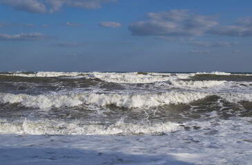 Stormy sea against a blue sky with clouds.