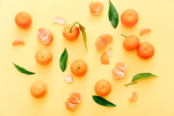 Fresh clementines with leaves on yellow background, top view