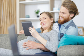 couple with pregnant woman using tablet together
