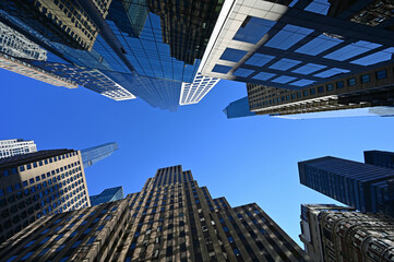 Fototapeta na wymiar Upward view of skyscrapers in New York City, New York against clear blue sky.