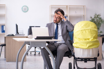Young male employee looking after new born at workplace