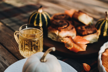 Thanksgiving festive table. Autumn style table setting with pumpkins, leaves and physalis. Pumpkin pie and cinnamon rolls. Cozy autumn scene. Flat lay. Fall styled composition.