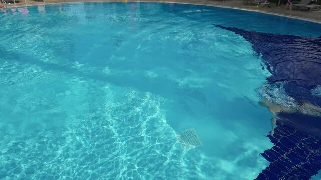 Active young woman diving in pool and splashing water. Lady relaxing on tropical resort.