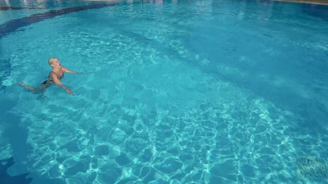 Active young woman diving in pool and splashing water. Lady relaxing on tropical resort.