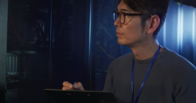 Asian male it technician using tablet checking computer server