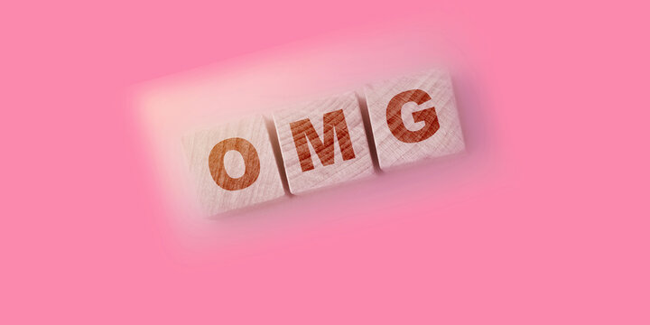 OMG written on a wooden cubes on soft pink background for Oh Mine God phrase