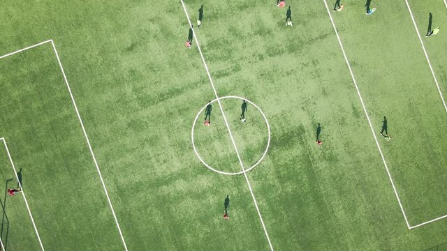 Aerial view of soccer players playing football on green sports stadium