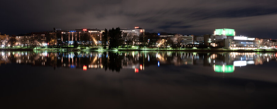 Beautiful city skyline casting reflections on the calm water during the night.