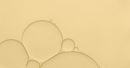 Oil bubble on water surface with pale yellow light effects background.