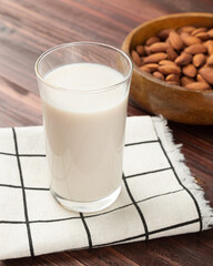 Almond milk in the glass with Almonds in wooden bowl on the table, Healthy snack, Vegetarian food.