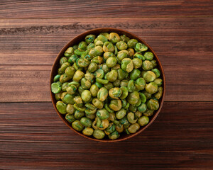 Top view of Salted green peas in wooden bowl on the table, Flat lay, Healthy snack, Vegetarian food.