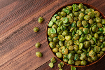 Top view of Salted green peas in wooden bowl on the table, Flat lay, Healthy snack, Vegetarian food.