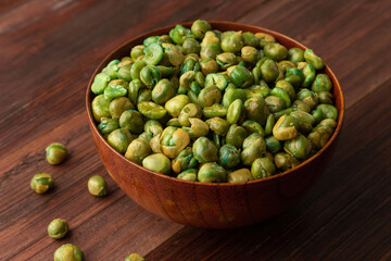 Salted green peas in wooden bowl on the table, Healthy snack, Vegetarian food.