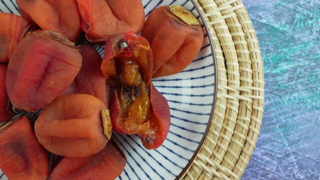 Dried persimmon in plate on wooden background. 4k resolution.