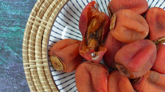 Dried persimmon in plate on wooden background. 4k resolution.