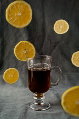 cup of tea with lemon. Lemon slices are falling in the background.