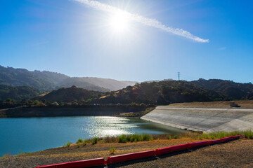 Hot sun shines over almost dried with low water lever Stevens Creek reservoir in San Francisco Bay Area, California