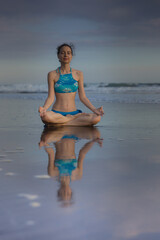 Beach yoga practice in Bali. Lotus pose. Padmasana. Hands in gyan mudra. Meditation and concentration. Zen life. Relaxation of body and mind. Yoga retreat. Water reflection. Copy space.