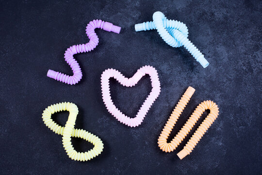 Multicolored bright tubes on black background. Anti-stress sensory figet plastic toy.