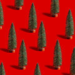 Pattern with green shining Christmas tree on red background. Bright minimal New Year layout with mini festive fir, xmas decor ornament, winter holiday