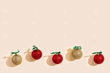 Christmas layout with shining red and golden Christmas balls, festive present, shadows on pale pink background. New Year holiday decorations