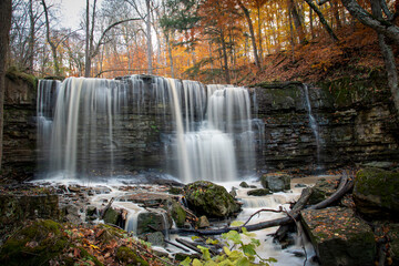 The blurred water of Terrace Falls, one of several waterfalls in Short Hills Provincial Park near St. Catherines, Ontario, cascades over a small cliff in a forest. - obrazy, fototapety, plakaty