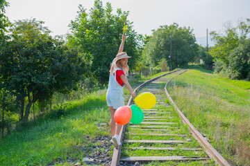 woman walking with balloons on the railroad