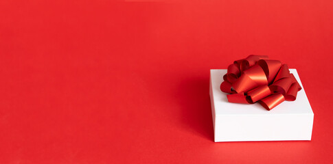 white gift box with red ribbon bow on red background. present for Christmas, new year, valentine day