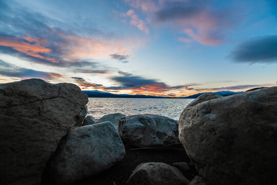 Landscape, scenic view of a pastel pink and blue cloudy sunset with rocky lake shore from northern Canada.