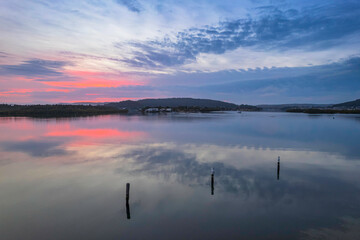 Soft and peaceful sunrise aerial waterscape with clouds and reflections