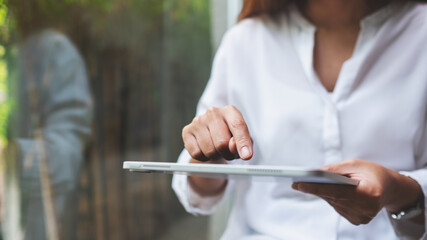 Closeup image of a woman holding and touching on digital tablet screen