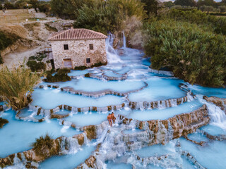 Toscane Italy, natural spa with waterfalls and hot springs at Saturnia thermal baths, Grosseto, Tuscany, Italy aerial view on the Natural thermal waterfalls couple at vacation at Saturnia Toscany - obrazy, fototapety, plakaty