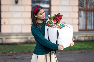 Fototapeta premium Attractive young woman with Christmas gift boxes outside, copy space.