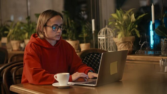 Young Caucasian woman freelancer or blogger working on laptop in cafe. College student using technology , online education, freelance